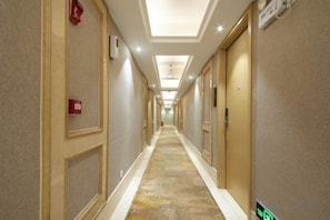 A hotel corridor with doors on both sides, a carpeted floor, and a fire alarm on the left wall. - Fuyue Hotel (Shenzhen)