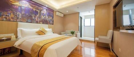 A modern hotel room with a large bed, a flat-screen TV, a desk with a chair, and a cityscape painting on the wall.
