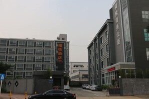 Un bâtiment sur lequel on peut voir une enseigne indiquant qu’il s’agit d’un hôtel. Des voitures sont garées devant, et un passage piéton est visible.