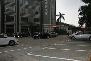 A parking lot with cars, a building with large windows, and a sign with Chinese characters. - Fuyue Hotel (Shenzhen)