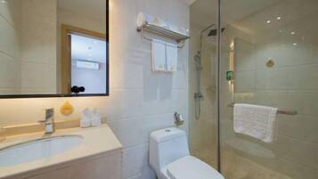 A modern bathroom with a glass-enclosed shower, a white sink, and a toilet.