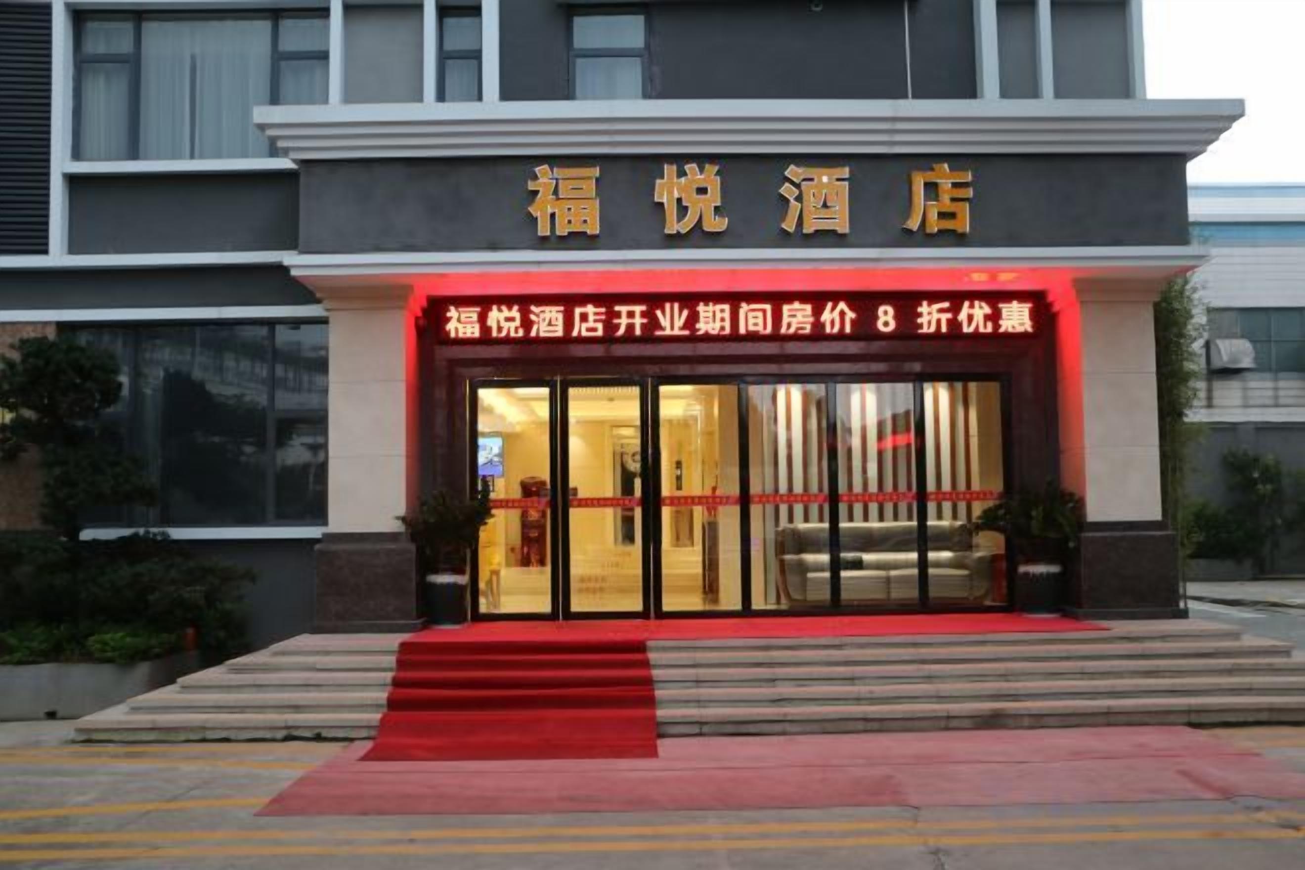 A hotel entrance with a red carpet leading up to the doors, a signboard above the entrance, and a staircase.