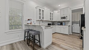 A kitchen with white cabinetry, a built-in microwave, and a stainless steel refrigerator. - Gorgeous, spacious home, steps to the 12,000sqft pool, recently renovated. Perfect for the whole family! (Panama City Beach)