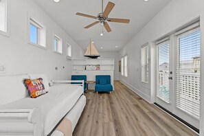 A spacious room with a bed, a ceiling fan, a small table, two chairs, and a window with blinds. - Gorgeous, spacious home, steps to the 12,000sqft pool, recently renovated. Perfect for the whole family! (Panama City Beach)