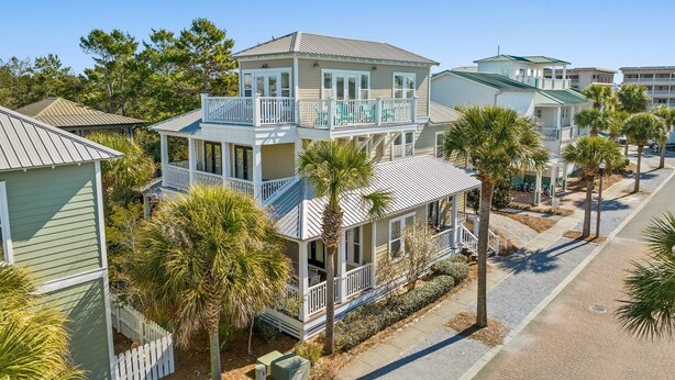 A coastal residential area with multi-story houses featuring balconies, palm trees, and a clear sky. - Gorgeous, spacious home, steps to the 12,000sqft pool, recently renovated. Perfect for the whole family! (Panama City Beach)