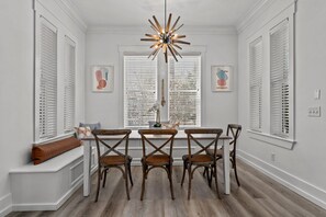 A dining area with a central table, four chairs, a bench with a cushion, and a unique ceiling light. - Gorgeous, spacious home, steps to the 12,000sqft pool, recently renovated. Perfect for the whole family! (Panama City Beach)
