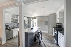 Una cocina moderna con armarios blancos, una isla central y una araña.