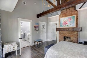 Amplia habitación con una cama grande, una chimenea y vistas a un baño con ducha y retrete.