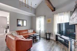 Ein Wohnzimmer mit Ledersofa, Couchtisch, Fernseher und Kamin.