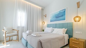 A modern bedroom with a large bed, a wooden nightstand, a chair, and a painting on the wall. - Kalami Beach - Villa Anastasia (Corfu)