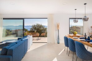 Ein modernes Interieur mit Essbereich, blau gepolsterten Sitzmöglichkeiten und Blick ins Freie.