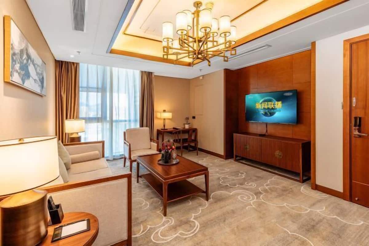 Une chambre d’hôtel équipée d’une télévision, d’un canapé, d’une table basse, d’une lampe, d’un bureau et d’une chaise.