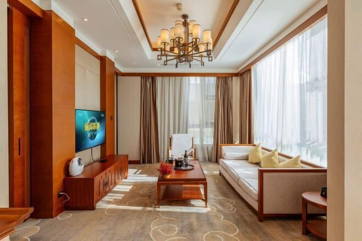 Une chambre d’hôtel équipée d’une télévision, d’un canapé, d’une table basse et de grandes fenêtres.
