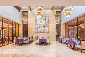 A spacious dining area with tables set for multiple guests, featuring a high ceiling and decorative lighting fixtures. - Yongchang Hotel (Baoshan)