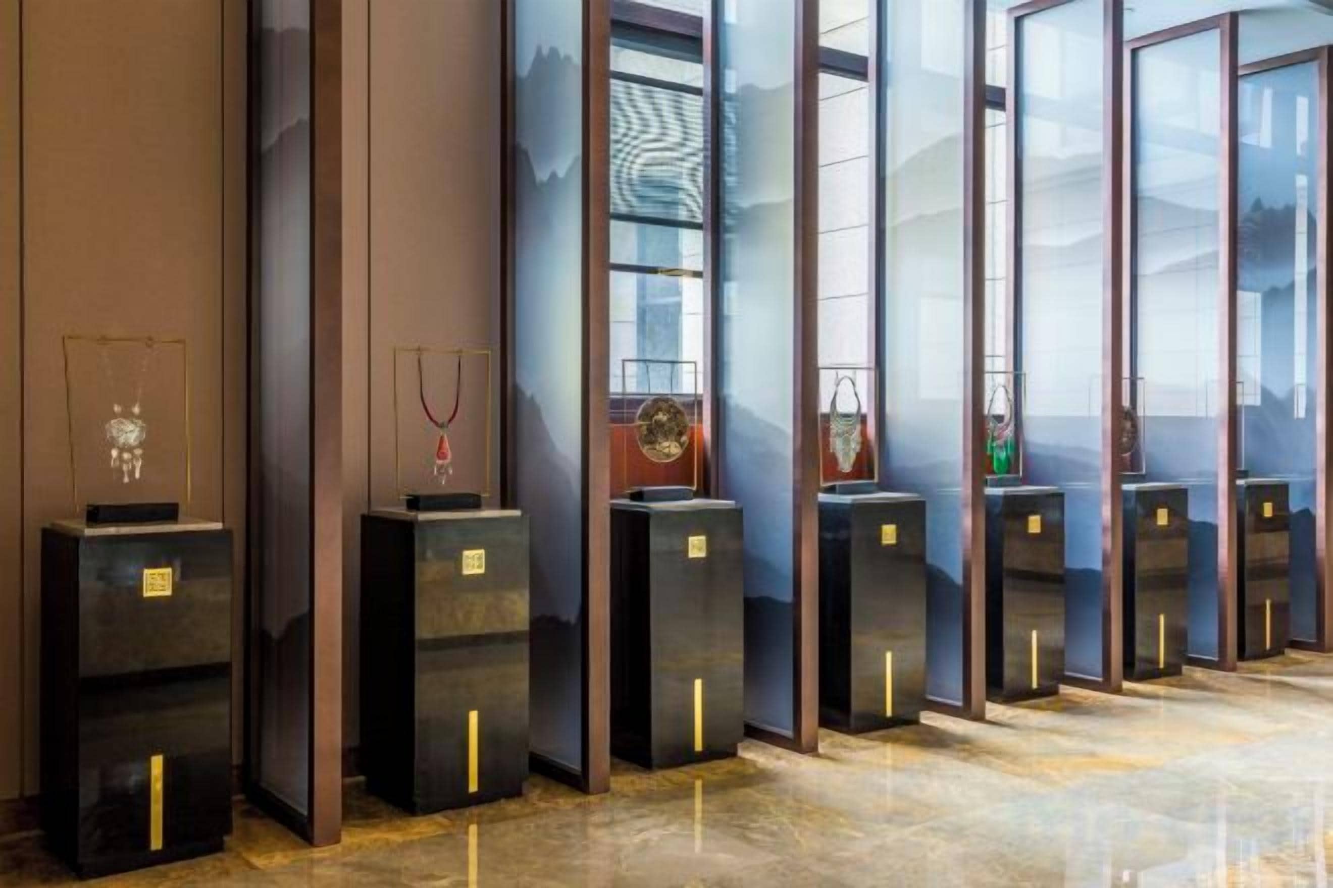 Une rangée de vitrines exposant des bijoux, probablement dans le hall d’un hôtel ou dans un espace d’exposition.