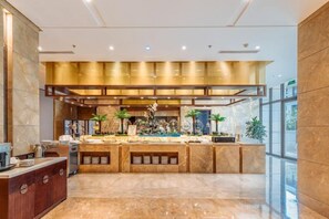 A modern hotel lobby with a marble reception desk, a large central counter, and a glass wall providing a view of the outdoors. - Yongchang Hotel (Baoshan)