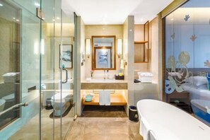 Un baño moderno con cabina de ducha de vidrio, un espejo grande, bañera y tocador con lavabo y toallero.