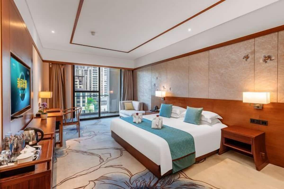 Une chambre d’hôtel avec un grand lit, un bureau avec une chaise, une télévision et une vue sur la ville.