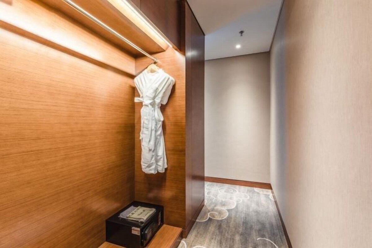 Un pasillo con pared de madera y una bata blanca colgada en un perchero.