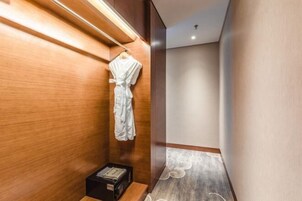 Un pasillo con pared de madera y una bata blanca colgada en un perchero.