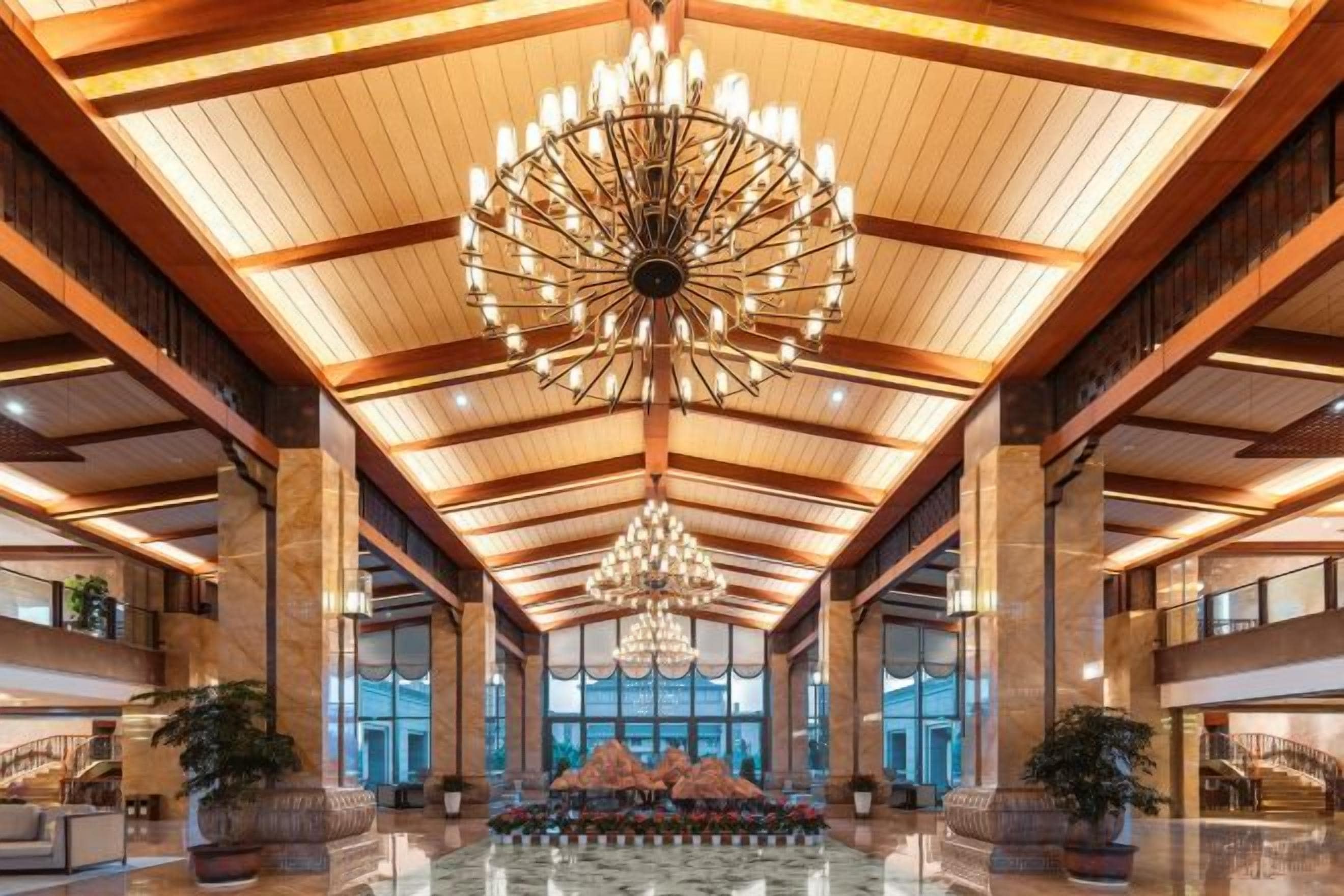 A spacious lobby with a high ceiling, large chandeliers, and a central seating area.