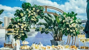 A table set up with various food items and floral decorations near a pool, with buildings in the background. - Yongchang Hotel (Baoshan)