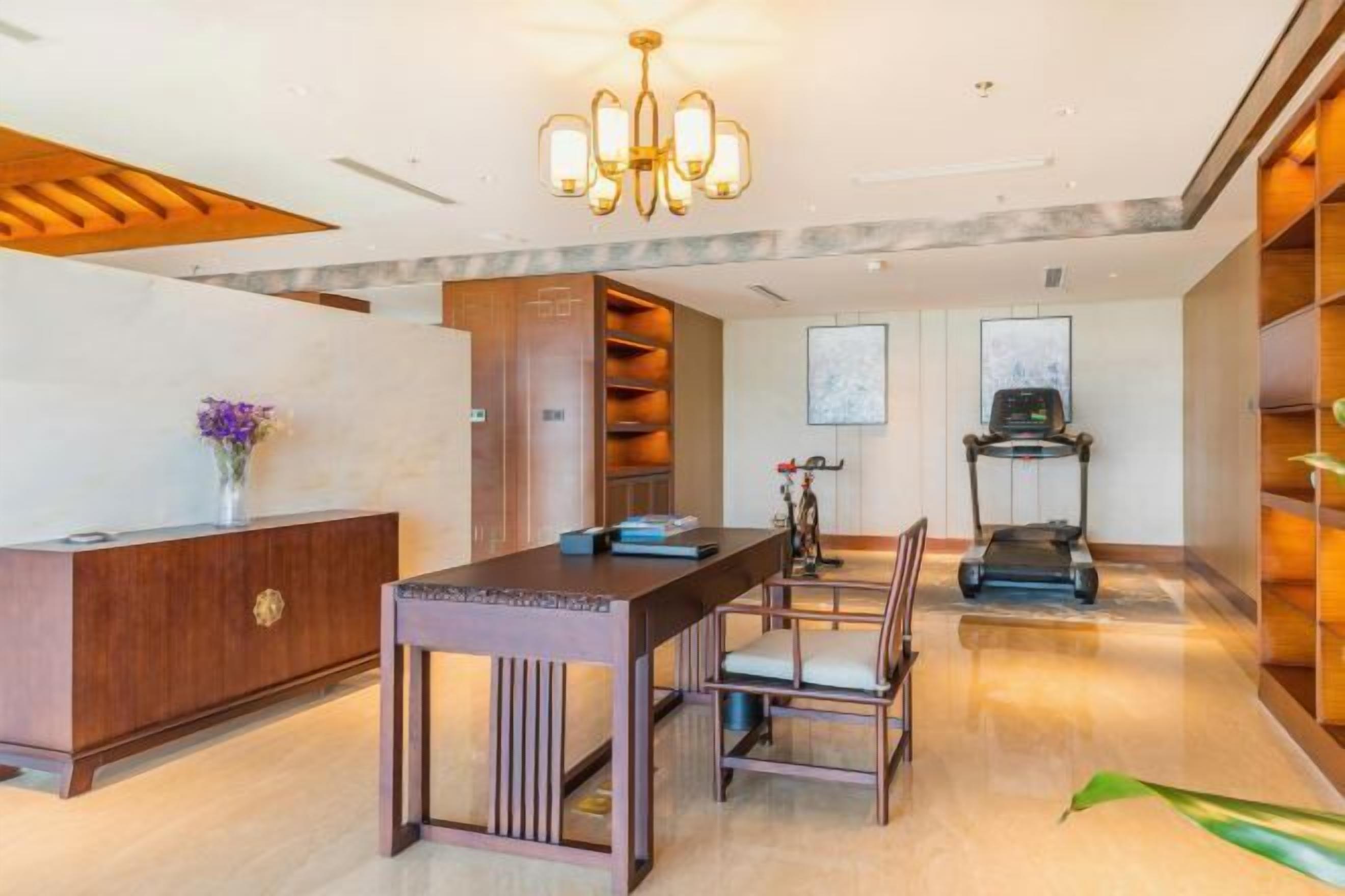 A modern hotel lobby with a reception desk, seating area, and a treadmill.