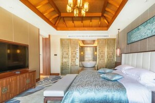 Un dormitorio con una cama grande, televisión, bañera y techo de madera.