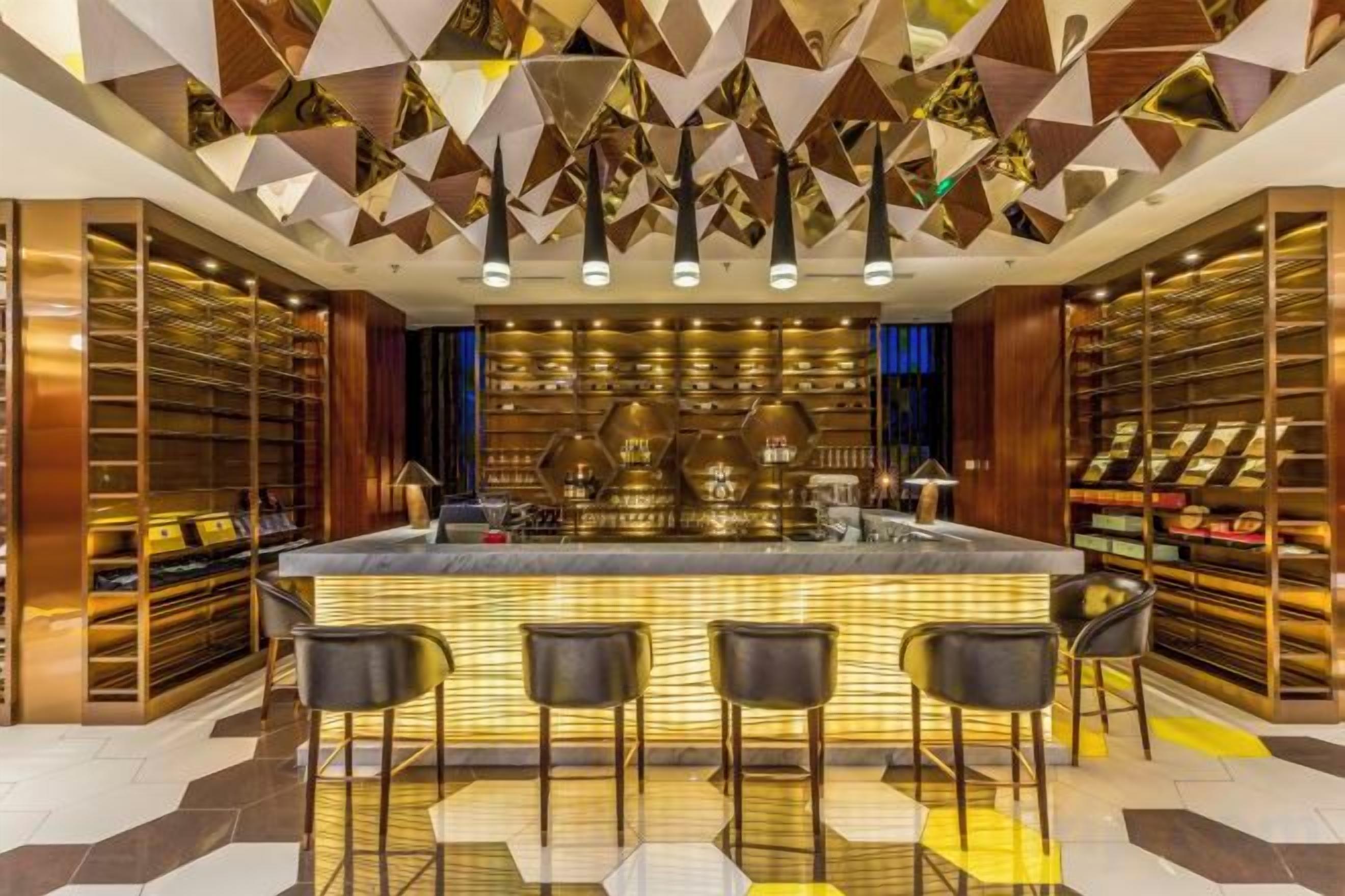 A bar area with a central bar counter, multiple seating options, and a patterned ceiling.