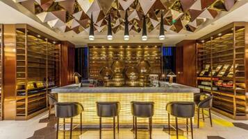 A bar area with a central bar counter, multiple seating options, and a patterned ceiling.