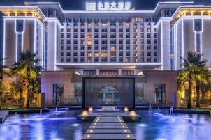 A hotel with a modern facade, a central entrance, and a water feature in front.
