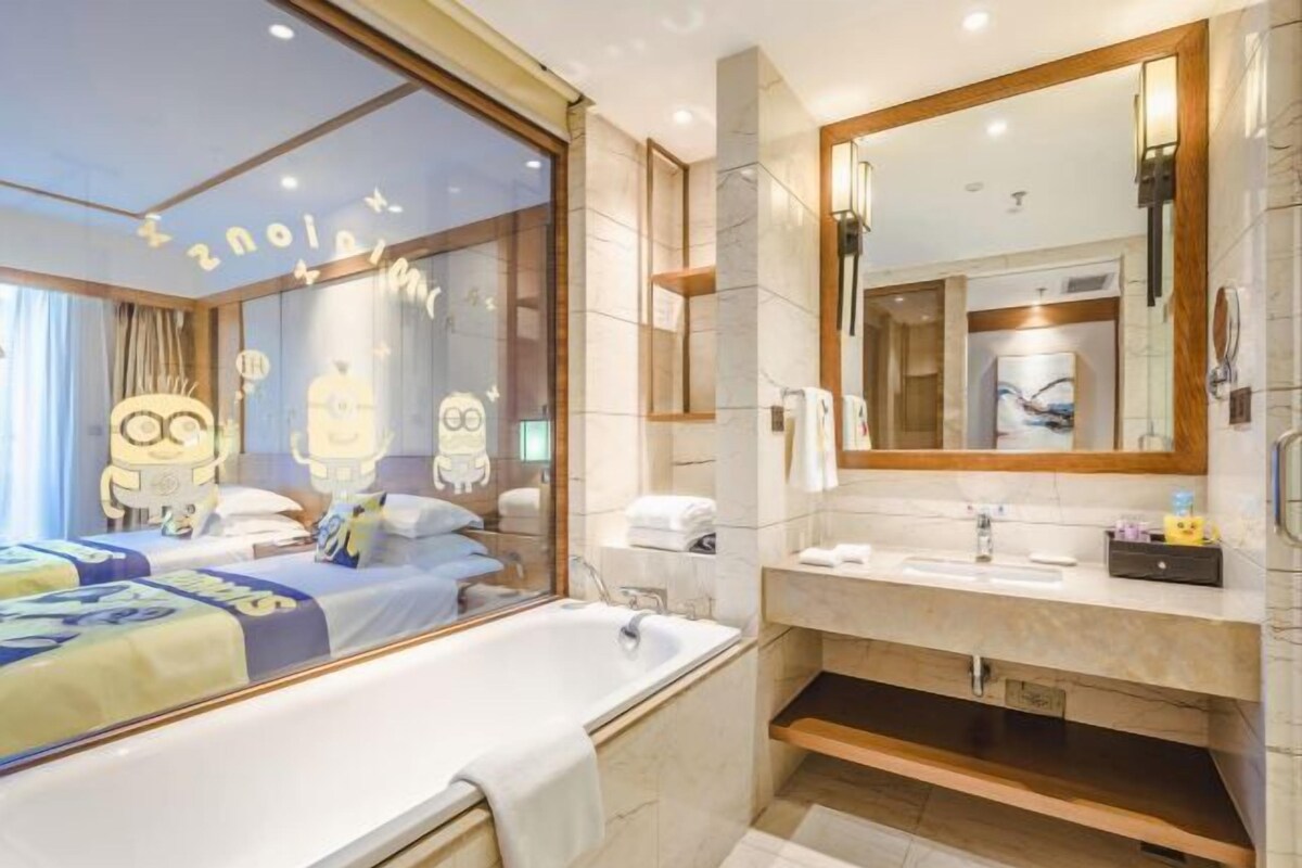 Una habitación de hotel moderna con una cama grande, un baño independiente con tocador y un espejo amplio.
