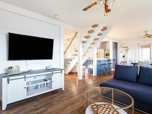 Ein modernes Wohnzimmer mit Flachbildfernseher, einem Glastisch und einem blauen Sofa.