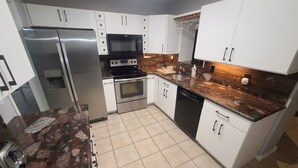 A modern kitchen with white cabinets, stainless steel appliances, a granite countertop, and a tiled floor. - Hollywood getaway near all points of interest (Hollywood)