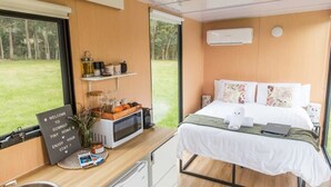 A compact room with a bed, a small kitchenette, a sign, and a view of the outdoors.