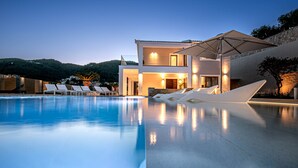 A modern hotel with a swimming pool, lounge chairs, and a well-lit entrance. - Kalami Beach - Villa Mara (Corfu)