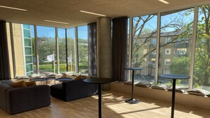 Un interior moderno con ventanas amplias, un conjunto de sofá y dos mesas redondas.