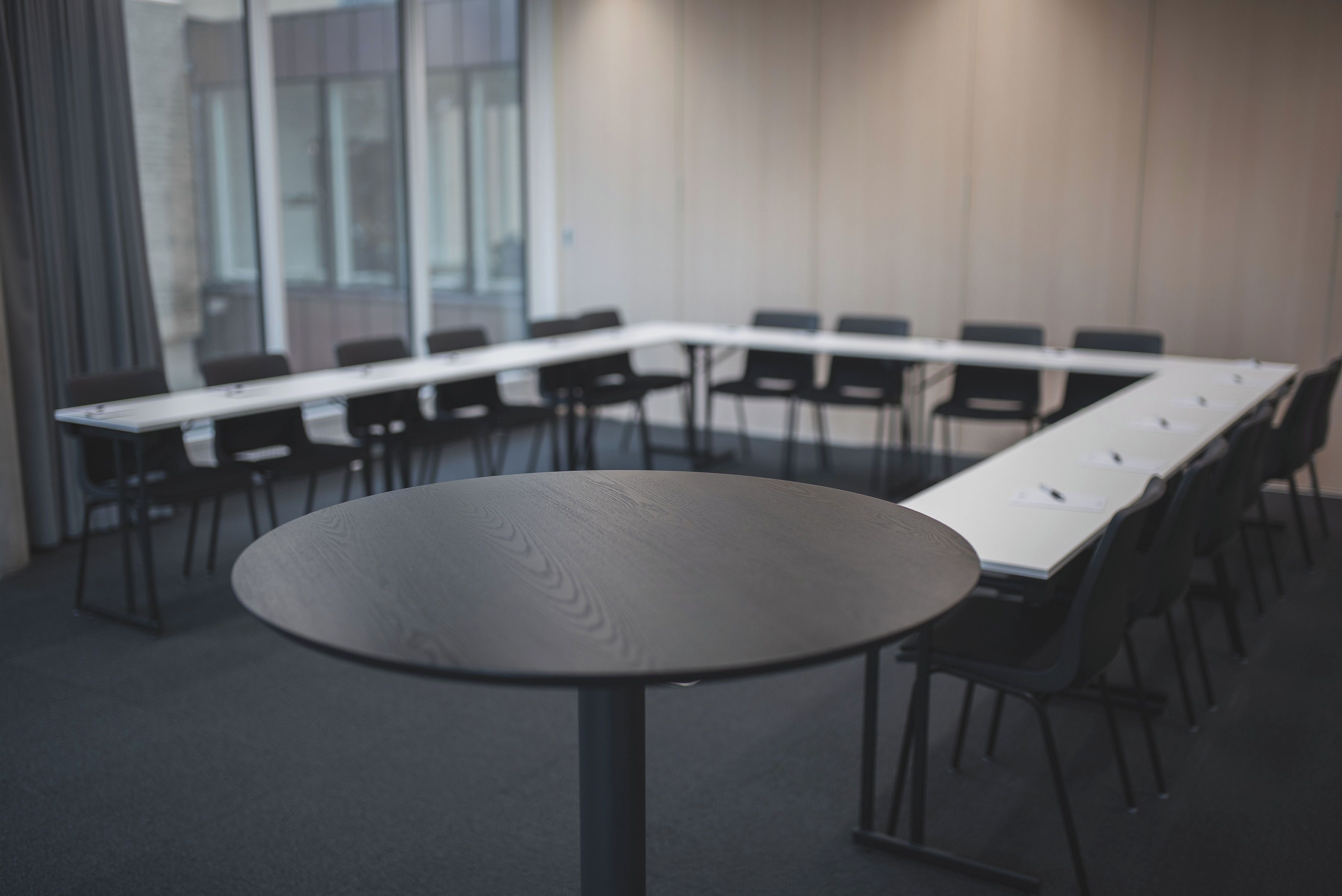 Une salle de conférence dotée d’une longue table et de chaises, de grandes fenêtres et d’un sol recouvert de moquette.