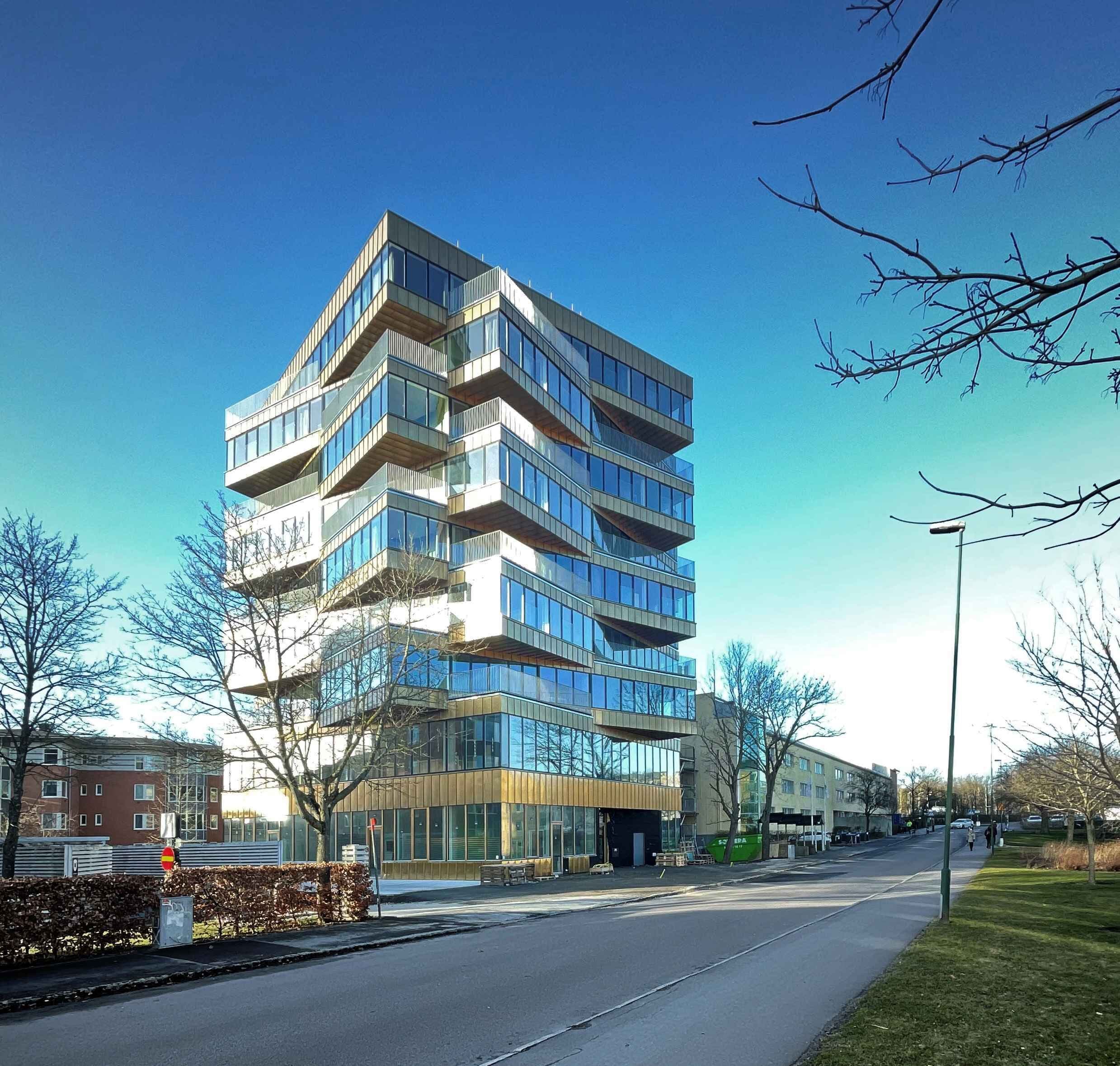 A modern multi-story building with a glass facade and balconies.