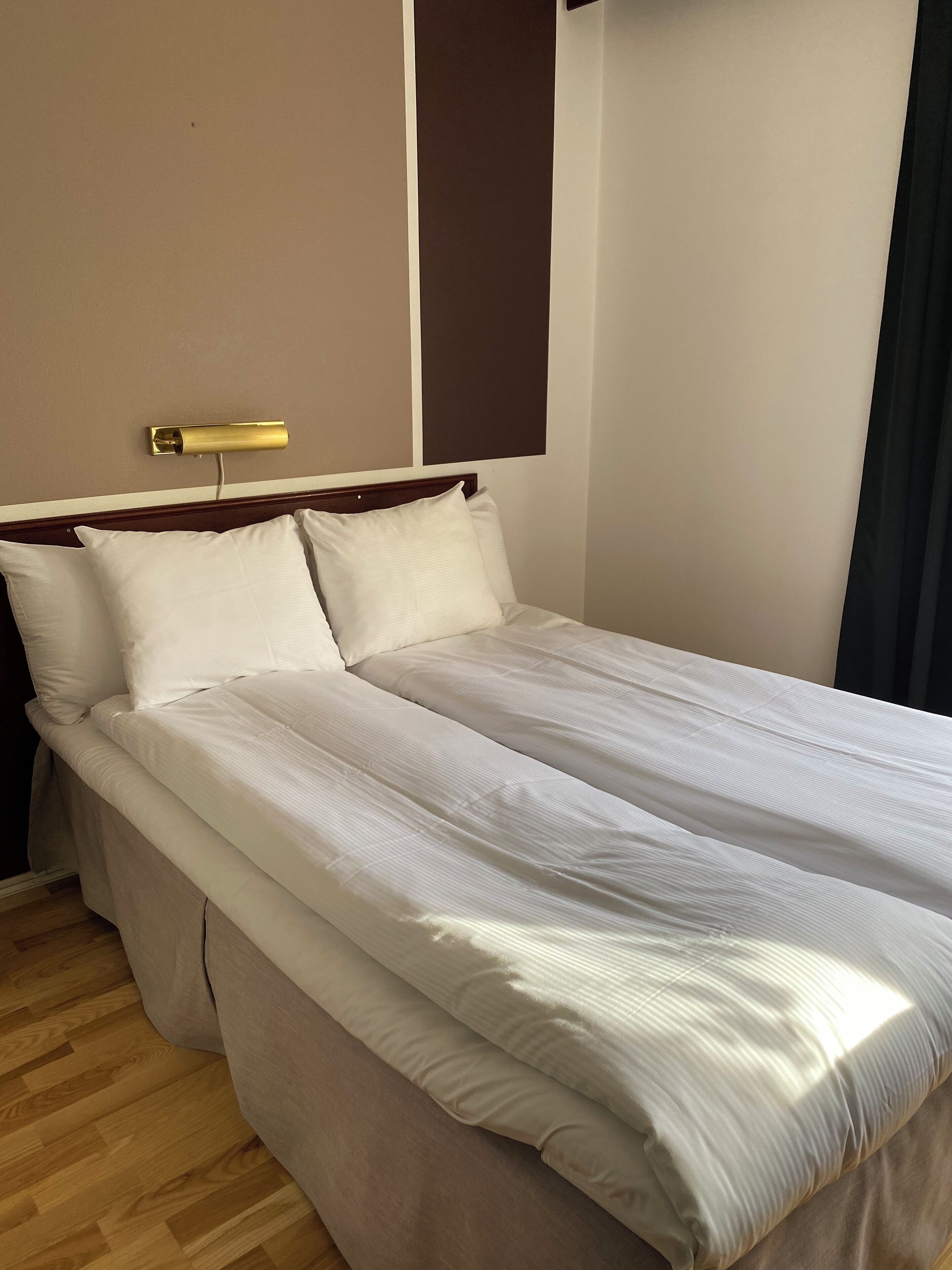 A neatly made bed with white linens in a hotel room.