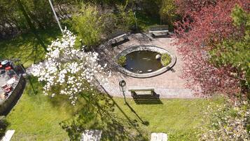 An aerial view of a park with a circular pond, benches, and a picnic area.