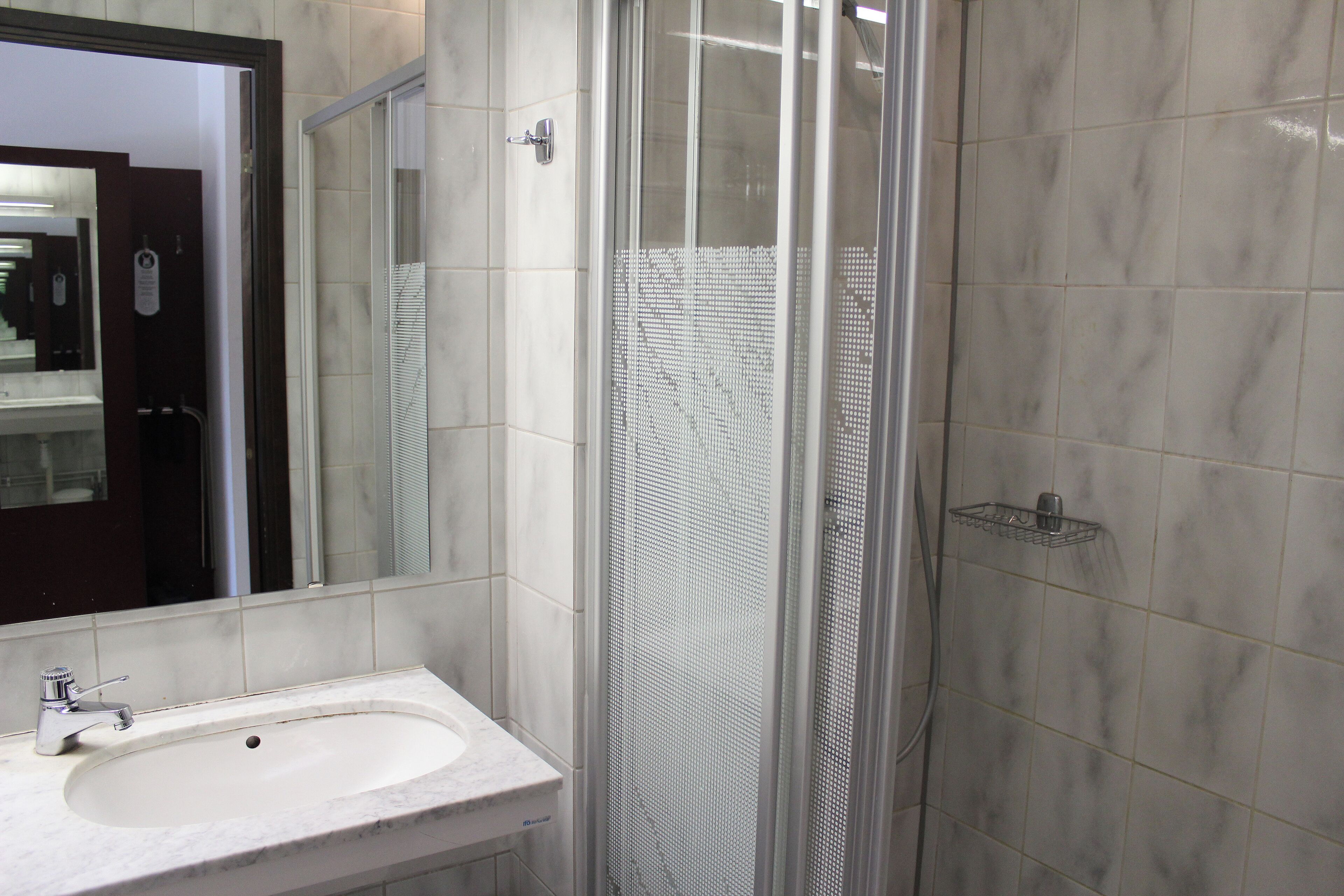 Un baño con lavabo, espejo y cabina de ducha.