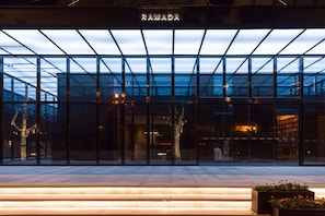 A modern building with a glass facade and a sign reading "RAMADA".