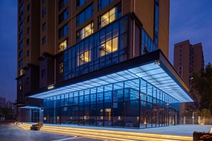 A modern hotel with a glass facade, a covered entrance, and a parking area. - Ramada by Wyndham Wuhan Hankou (Wuhan)