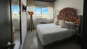 Une chambre à coucher avec un lit, un ventilateur de plafond, une fenêtre avec des rideaux et une vue sur l’extérieur.
