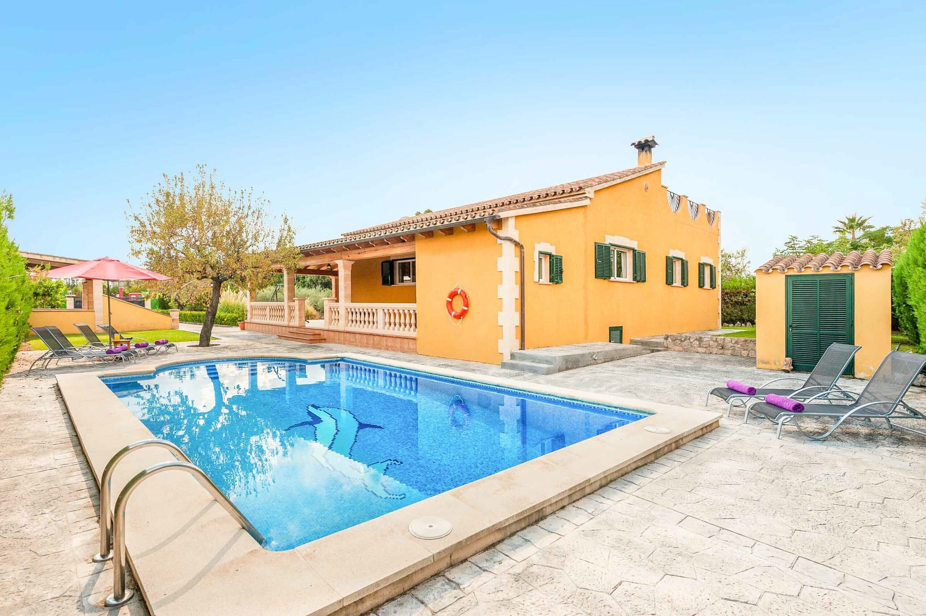 A swimming pool with a clear blue water, surrounded by a stone deck.
