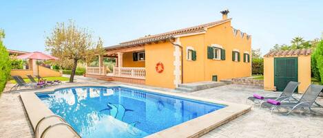 A swimming pool with a clear blue water, surrounded by a stone deck.
