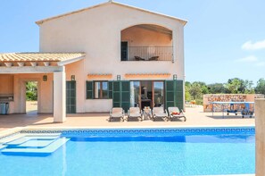 A two-story house with a swimming pool, outdoor seating, and a covered patio area.