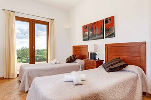 A hotel room with two beds, a wooden headboard, a nightstand, and a window with curtains.