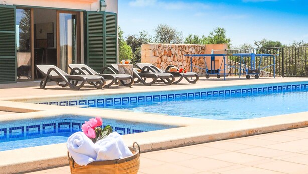 Zona de piscina con sillones de descanso, un muro de piedra y un carrito.